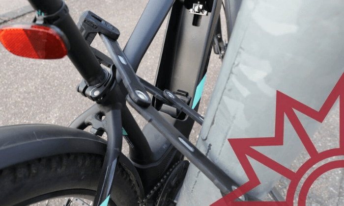Fahrrad mit Faltschloss gegen Diebstahl gesichert an einem Laternenpfahl.