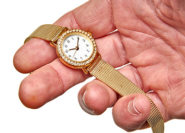 Eine goldene Armbanduhr liegt in einer Hand