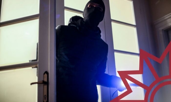 Maskierter Mann mit Taschenlampe öffnet Tür in Wohnung