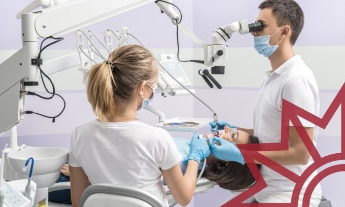 Eine Frau wird von einem Zahnarzt behandelt, eine Praxishilfe assistiert